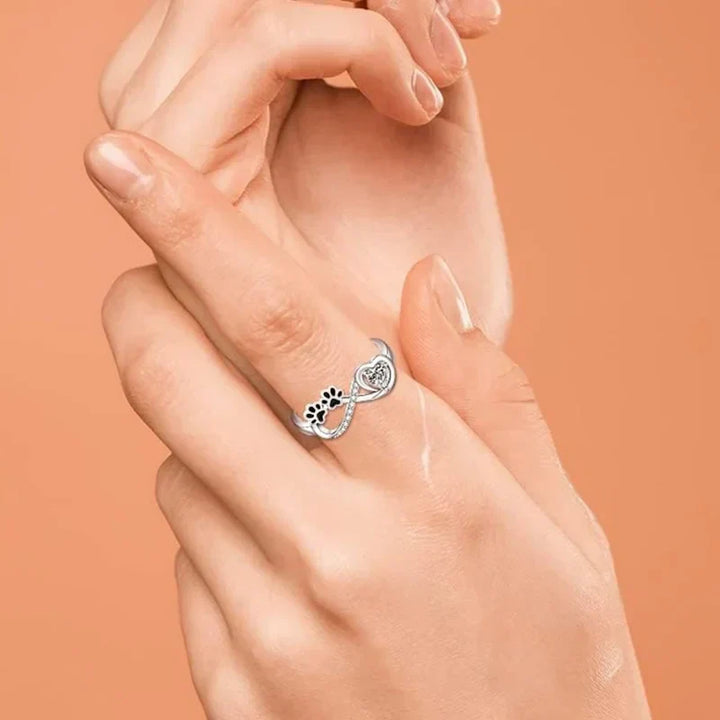 Ring mit pfotenförmigen Zirkonia-Steinen, Herz- und Unendlichkeitssymbol.